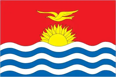 The flag of Kiribati presents a red upper half with a golden frigate bird flying over a rising sun of seventeen rays, above a lower blue half with three white wavy stripes. The design vividly evokes ocean, land, culture, and national identity.